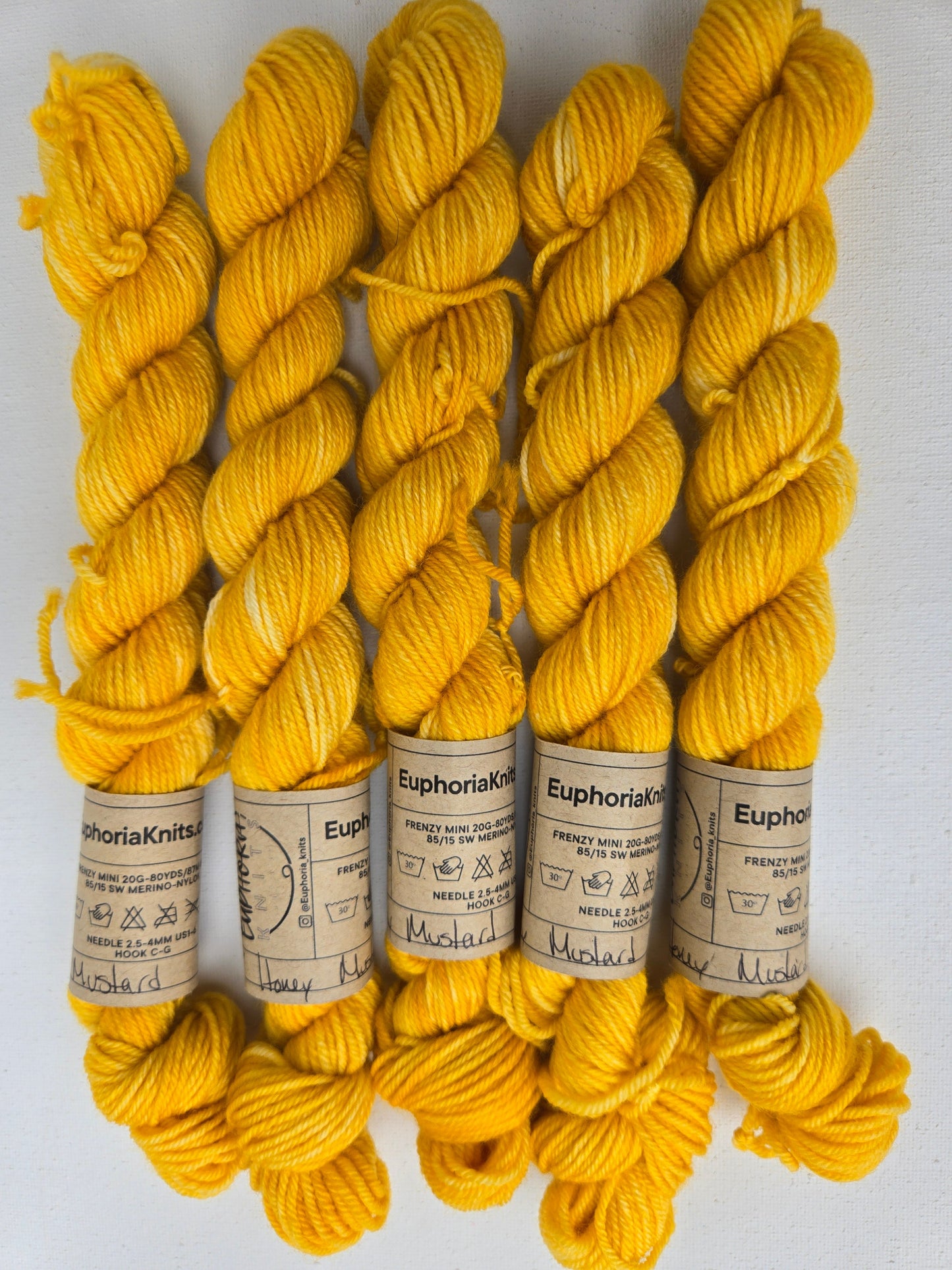 Yellow yarn skeins with labels on a white background