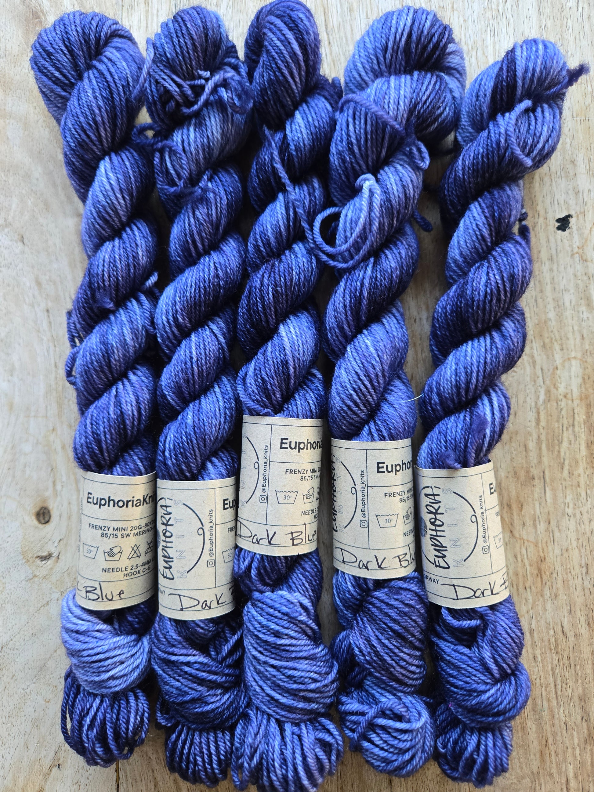 Blue yarn skeins with labels on a wooden surface