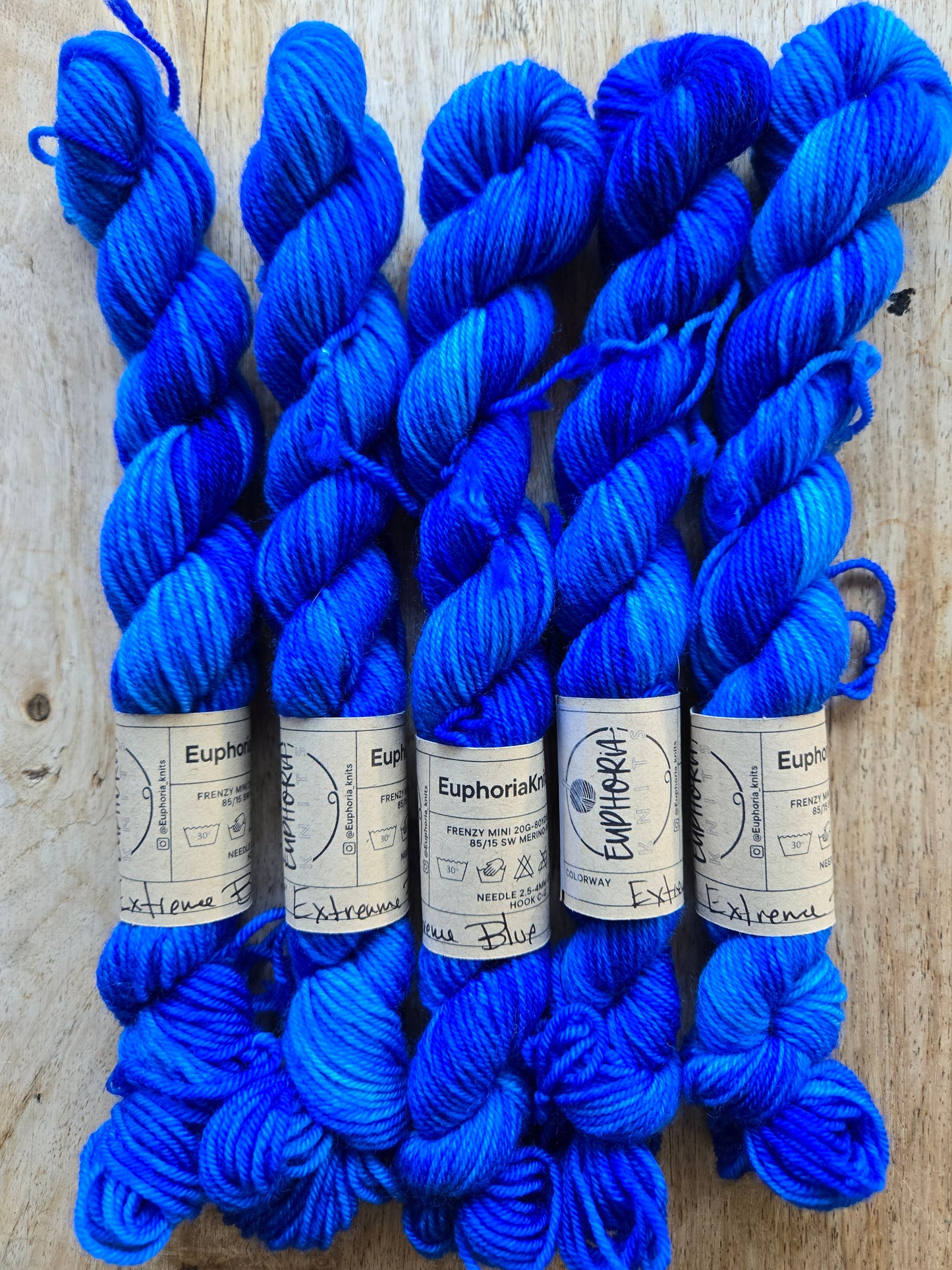 Blue yarn skeins with labels on a wooden surface
