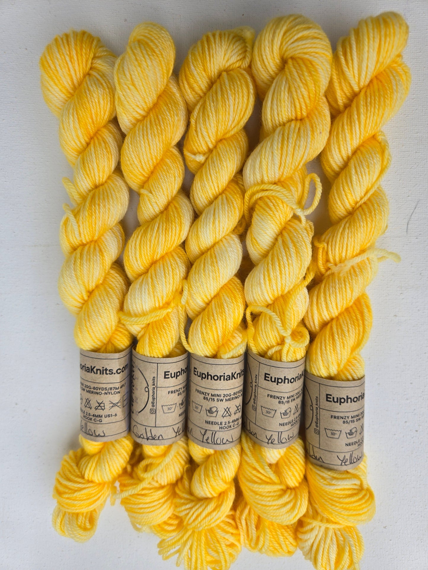 Yellow yarn skeins with labels on a white background