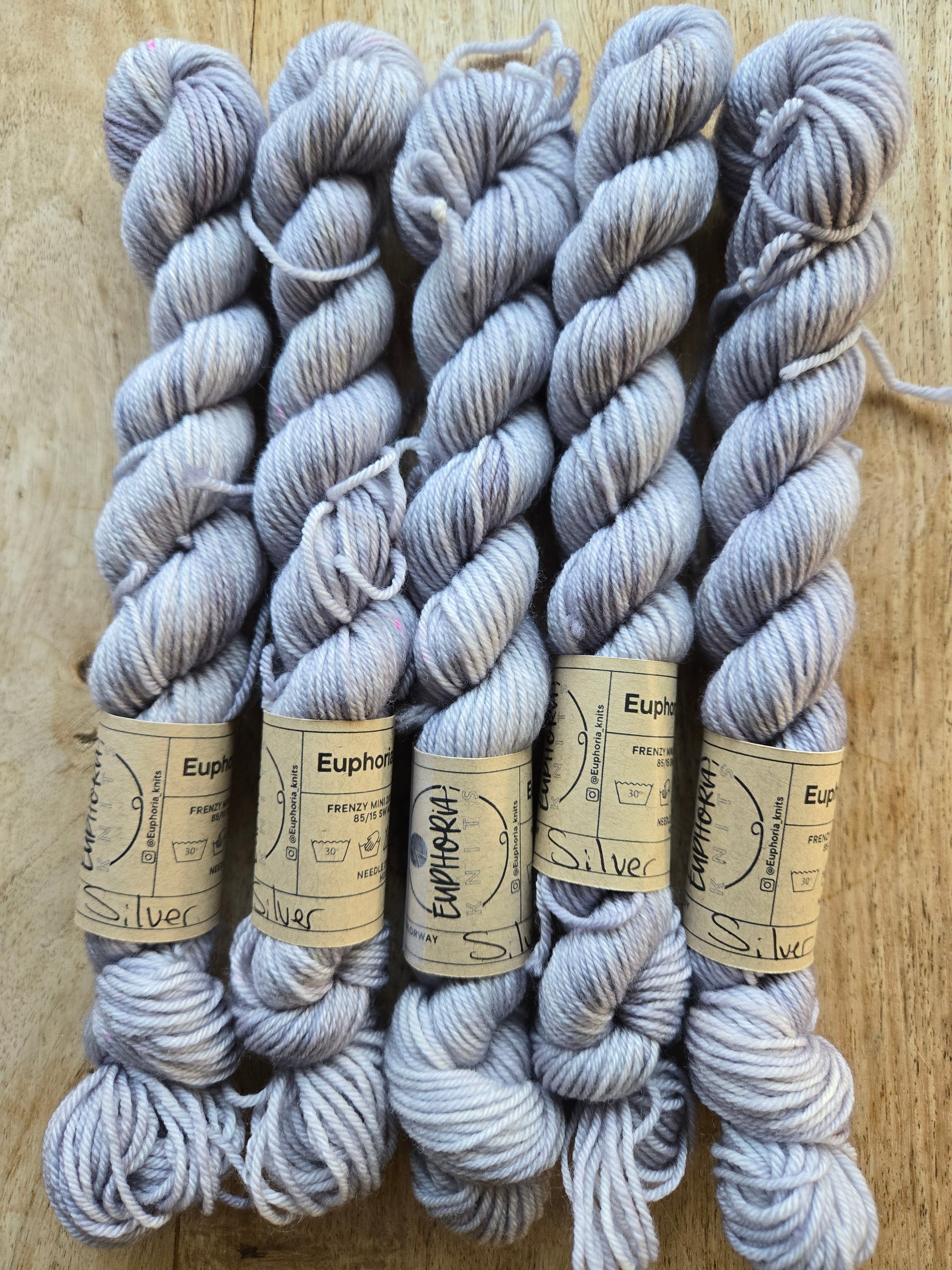 Gray yarn skeins with labels on a wooden surface