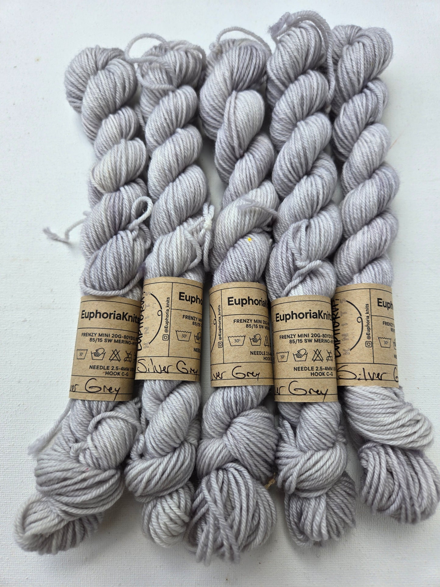 Gray yarn skeins with labels on a white background